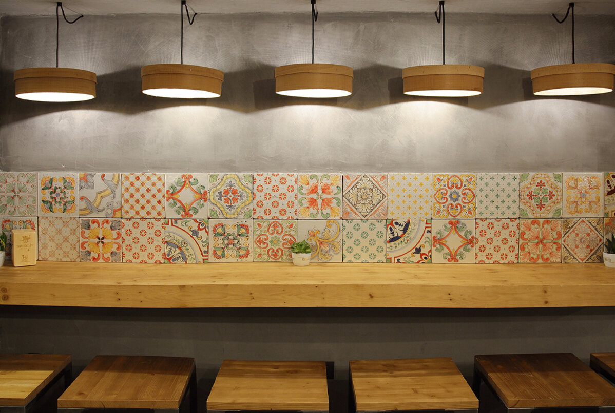 Sicilian tiles adorning a modern wall in a cafe with stylish lighting