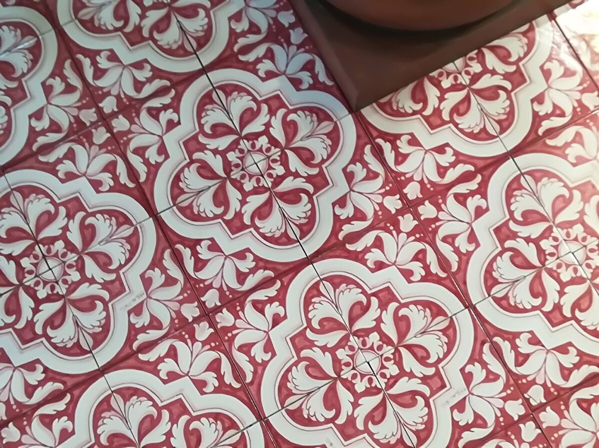 Red and white Sicilian tiles with floral patterns, handcrafted Mediterranean design.