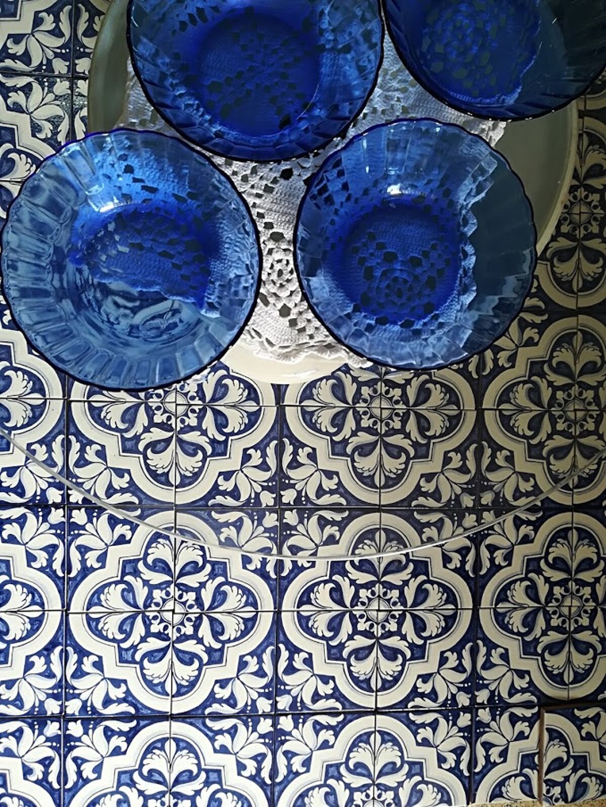 Blue glass bowls on Sicilian tiles with intricate Mediterranean design.
