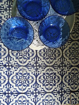 Blue glass bowls on Sicilian tiles with intricate Mediterranean design.