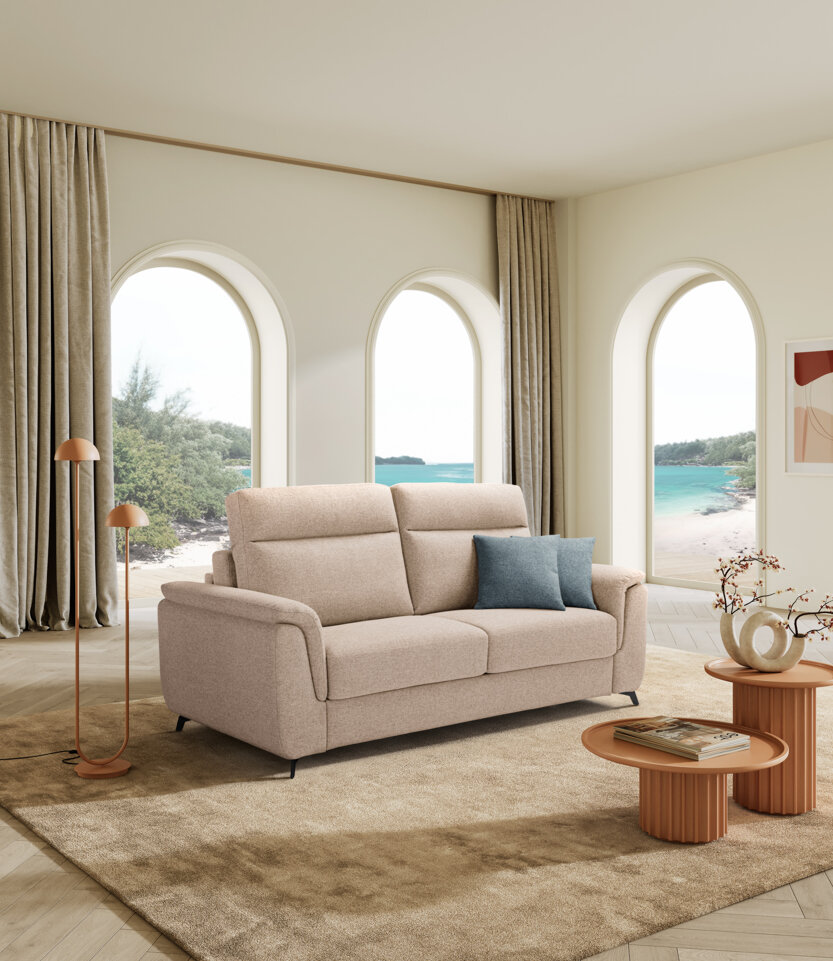 Divano letto beige in un salotto moderno con vista mare, artigianalità Made in Italy.