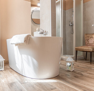 Bathroom with a freestanding bathtub, cozy chair, and wooden floor at Miele Apartment. Bathroom with a freestanding bathtub, cozy chair, and wooden floor at Miele Apartment.
