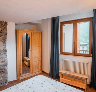 Camera con parete in pietra, armadio in legno e finestra Camera con parete in pietra, armadio in legno e finestra