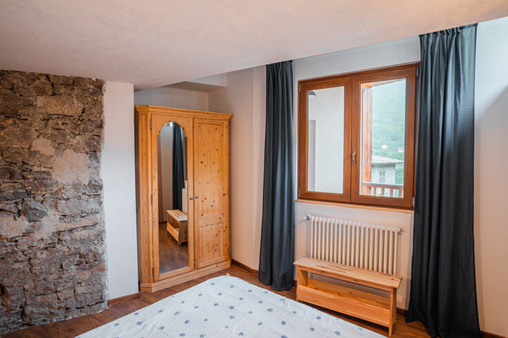 Camera da letto con armadio in legno e parete in pietra, appartamento La Torre Camera da letto con armadio in legno e parete in pietra, appartamento La Torre