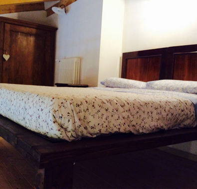 Letto matrimoniale in legno con copriletto floreale in una camera accogliente Letto matrimoniale in legno con copriletto floreale in una camera accogliente