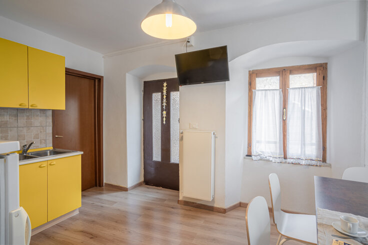 Interno di un appartamento con cucina moderna gialla, tavolo da pranzo e finestra luminosa Interno di un appartamento con cucina moderna gialla, tavolo da pranzo e finestra luminosa