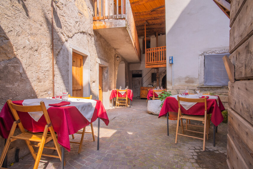 Cortile di un ristorante tradizionale con tavoli apparecchiati, agriturismo in Trentino