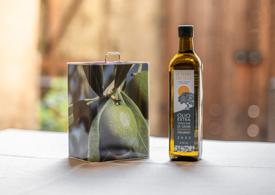 Bottiglia di olio extravergine di oliva biologico Le Terre del Sole e lattina con immagine di oliva.