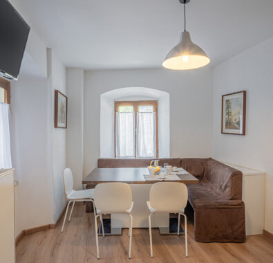 Spazioso angolo pranzo in appartamento con tavolo, sedie e divano ad angolo, ideale per prenotazioni online e comfort. Spazioso angolo pranzo in appartamento con tavolo, sedie e divano ad angolo, ideale per prenotazioni online e comfort.