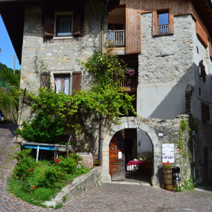 Casa rustica in pietra con arco e fiori, giornata soleggiata Casa rustica in pietra con arco e fiori, giornata soleggiata