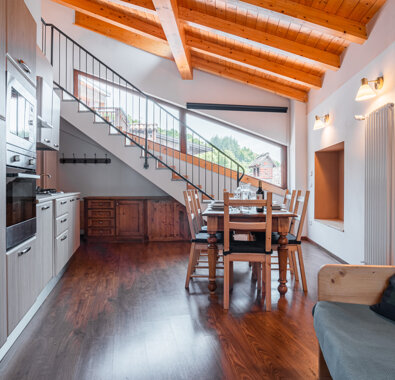 Interno di appartamento con cucina moderna, tavolo da pranzo e soffitto in legno Interno di appartamento con cucina moderna, tavolo da pranzo e soffitto in legno