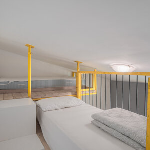 Soppalco con letto singolo, struttura in legno gialla e lampada a soffitto Soppalco con letto singolo, struttura in legno gialla e lampada a soffitto