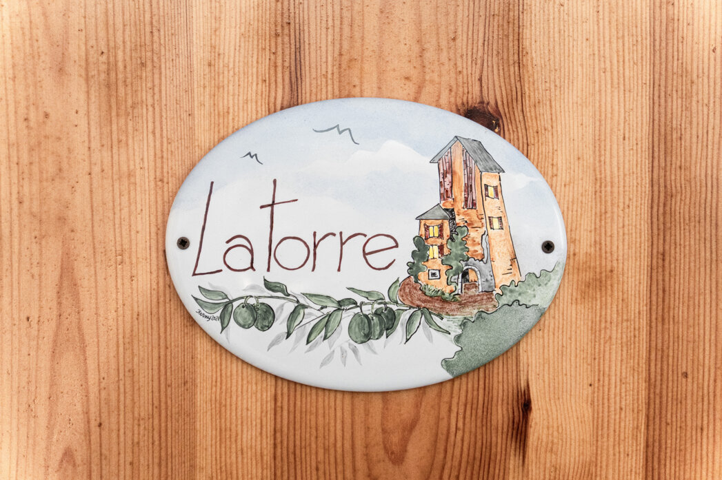 Insegna in ceramica con illustrazione torre e testo 'Latorre'