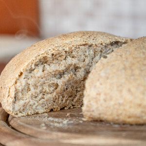 Pane integrale appena sfornato su tagliere di legno Pane integrale appena sfornato su tagliere di legno