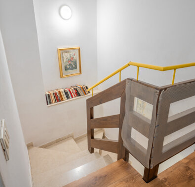 Scala interna con corrimano giallo e libreria a parete Scala interna con corrimano giallo e libreria a parete