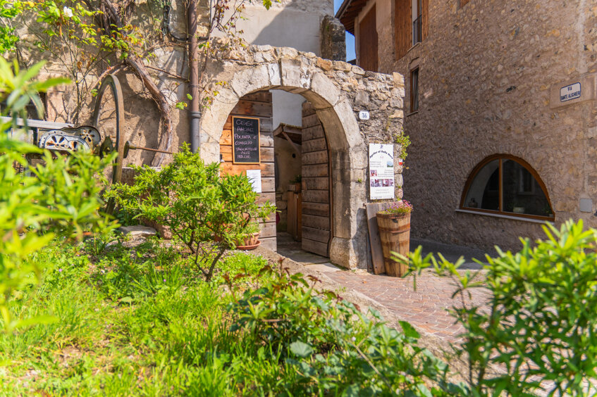 Ingresso di un ristorante tradizionale in un agriturismo in Trentino, circondato da vegetazione.