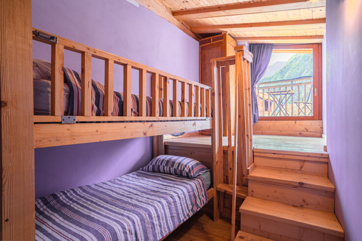 Camera con letti a castello in legno e pareti lilla, vista panoramica dalle finestre.