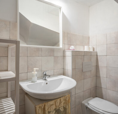 Bagno con lavabo, specchio e WC in appartamento con comfort e dotazioni moderne Bagno con lavabo, specchio e WC in appartamento con comfort e dotazioni moderne