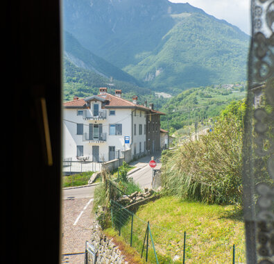 Vista montagna attraverso finestra in appartamento con case bianche e vegetazione Vista montagna attraverso finestra in appartamento con case bianche e vegetazione