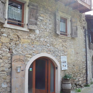 Entrata di una casa in pietra con finestre e balcone in legno Entrata di una casa in pietra con finestre e balcone in legno