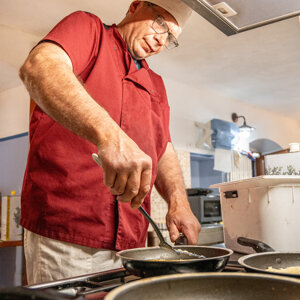 Cuoco in cucina mentre prepara del cibo in padella Cuoco in cucina mentre prepara del cibo in padella