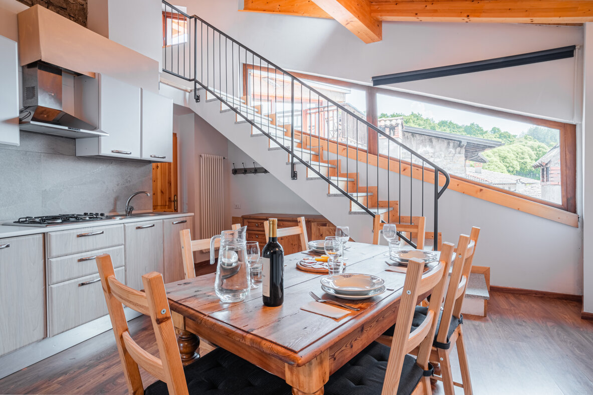 Interno appartamento con scala in legno e tavolo da pranzo apparecchiato Interno appartamento con scala in legno e tavolo da pranzo apparecchiato