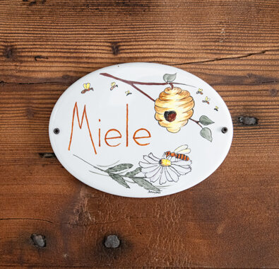 Decorative ceramic sign with drawn beehive and flowers labeled 'Miele' for Miele Apartment. Decorative ceramic sign with drawn beehive and flowers labeled 'Miele' for Miele Apartment.