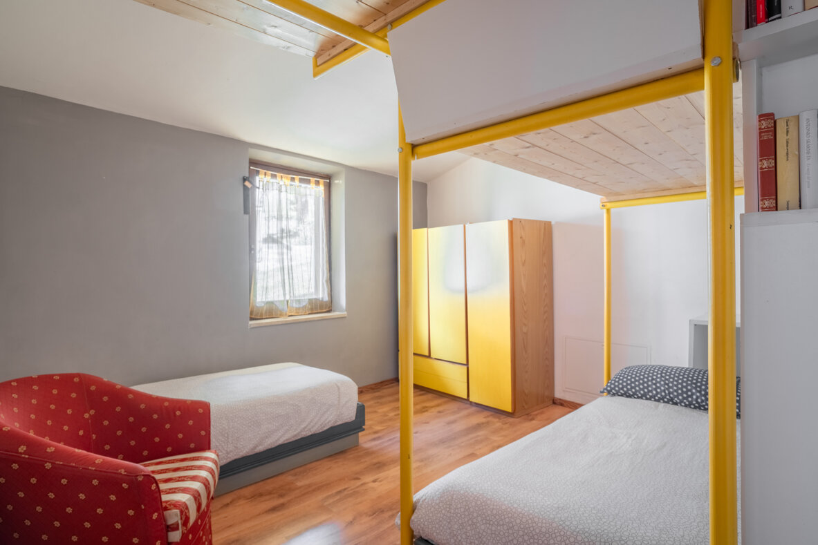 Camera da letto moderna con due letti singoli, armadio giallo e poltrona rossa. Camera da letto moderna con due letti singoli, armadio giallo e poltrona rossa.