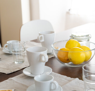 Tavola apparecchiata con tazze, bicchieri e frutta in appartamento confortevole Tavola apparecchiata con tazze, bicchieri e frutta in appartamento confortevole