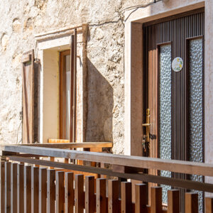 Ingresso di una casa in pietra con porta in legno e balcone. Ingresso di una casa in pietra con porta in legno e balcone.