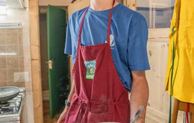 Giovane cuoco serve arrosto in una cucina tradizionale italiana.