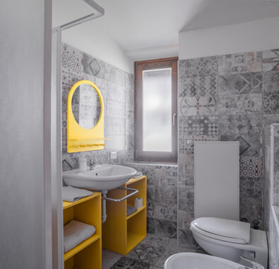 Bagno moderno con piastrelle decorate, specchio giallo e lavabo Bagno moderno con piastrelle decorate, specchio giallo e lavabo