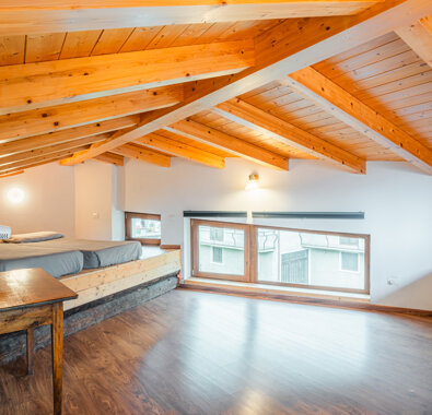 Sottotetto in legno luminoso con letto e finestre grandi Sottotetto in legno luminoso con letto e finestre grandi