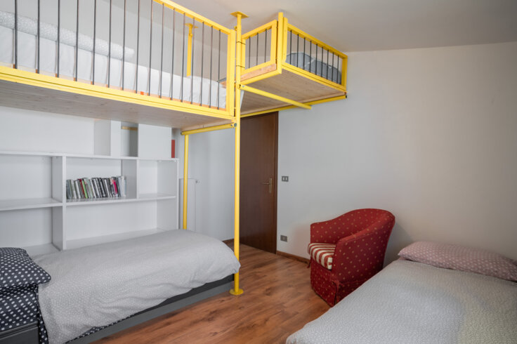 Camera con letto a castello moderno e poltrona rossa, pavimento in legno. Camera con letto a castello moderno e poltrona rossa, pavimento in legno.