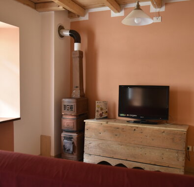 Interno di appartamento con stufa in ghisa e TV, arredato in stile rustico Interno di appartamento con stufa in ghisa e TV, arredato in stile rustico