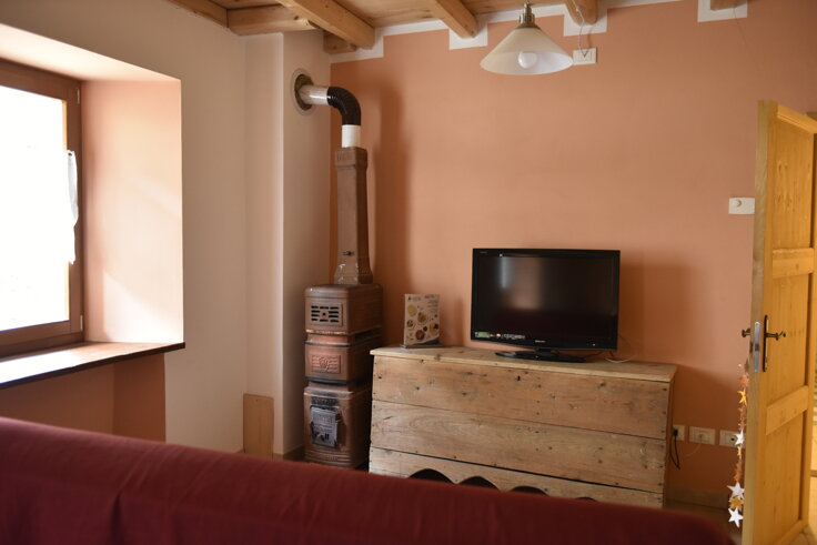 Angolo soggiorno con stufa antica e TV, Appartamento Rosso, comfort e dotazioni Angolo soggiorno con stufa antica e TV, Appartamento Rosso, comfort e dotazioni
