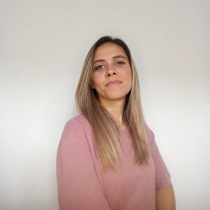 Donna sorridente con capelli lunghi, indossa una maglia rosa, sfondo bianco.