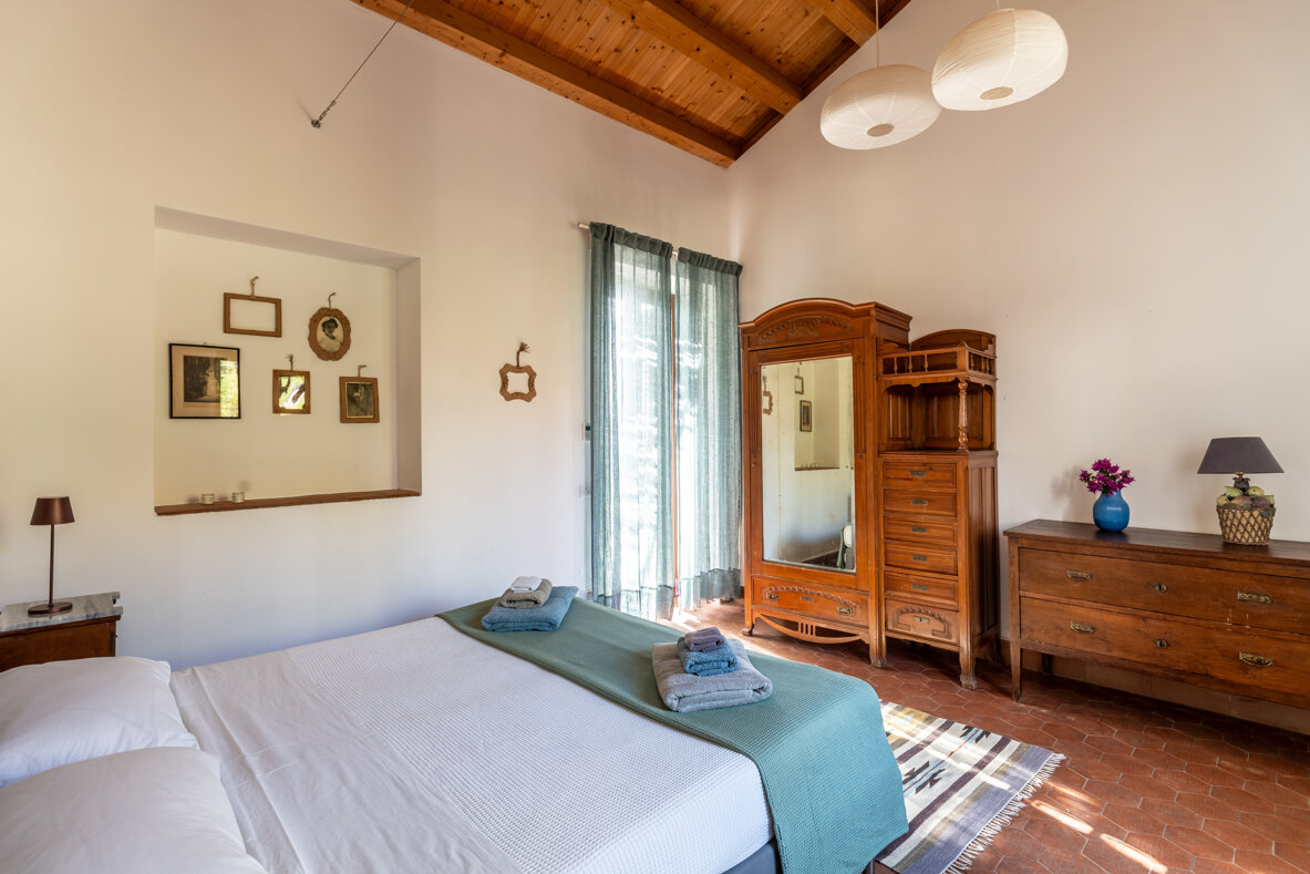 Bedroom with double bed and vintage decor, featuring wooden wardrobe and terrace access.