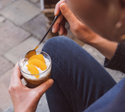 Persona che mangia un dessert cremoso con fette di agrumi Persona che mangia un dessert cremoso con fette di agrumi