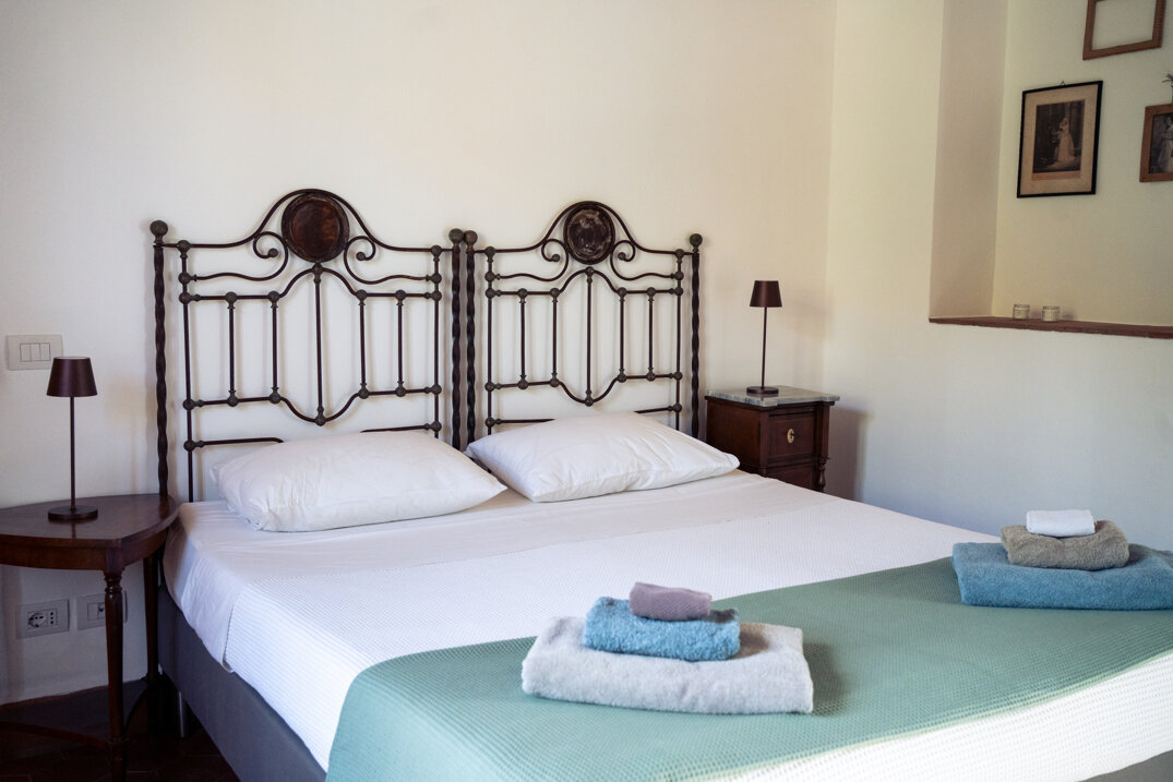 Cozy bedroom in a vacation apartment with vintage furniture and large window offering natural light.