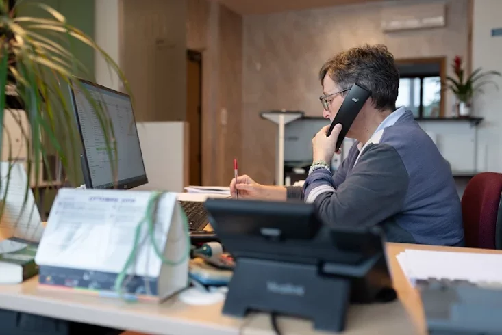 Persona al telefono in ufficio davanti al computer