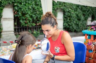 Animatrice mostra allo specchio una bimba che ha appena pitturato nel viso