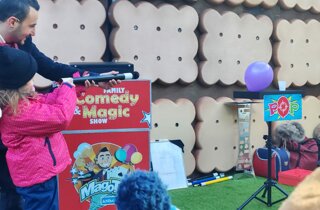 Mago Taz con una bambina fanno la magia con la bacchetta magica e un palloncino
