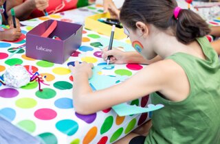 Bambina con un arcobaleno dipinto sul viso disegna nel laboratorio del mago Taz