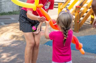 Animatrice da una scultura di palloncini a forma di cuore a una bambina felice