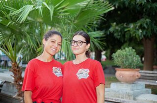 Due giovani animatrici sorridenti con la maglia a logo Mago Taz