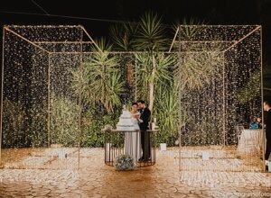 Luxury destination wedding in Sicily with a couple cutting the cake under luminous decorations.