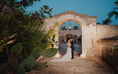 Luxurious Sicilian destination wedding couple embracing under stone archway