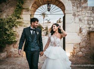 Bride and groom walking hand in hand at a rustic stone archway, Sicily wedding.