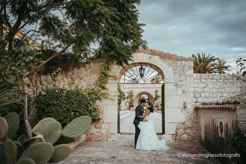 Couple embracing in scenic Sicilian garden gateway, ideal for luxury destination weddings.